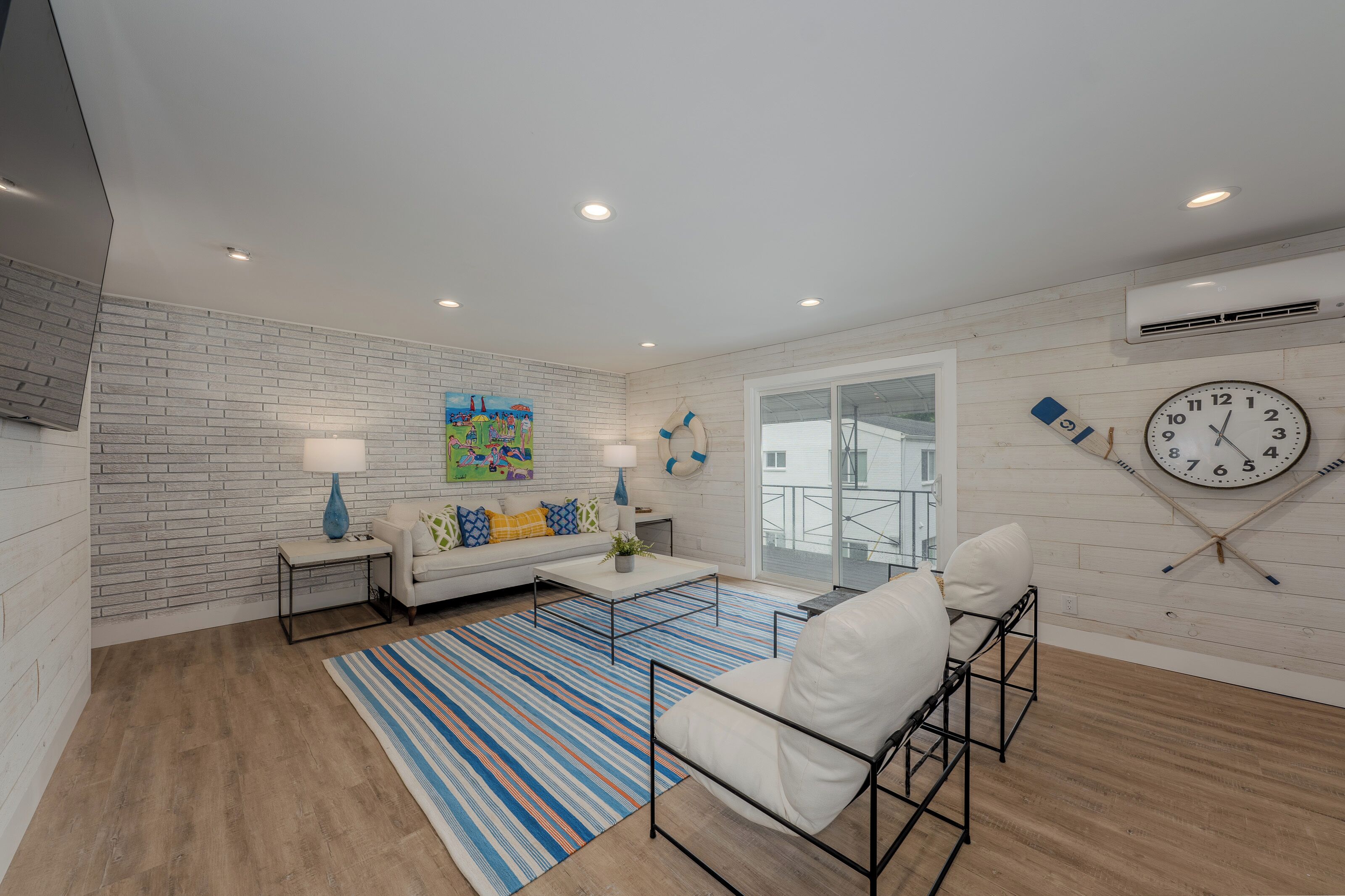A modern living room with a white brick wall, a large clock, and a view to the outside.