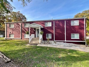A two-story building with a red brick exterior, a white front porch, and a small front yard. - Sunset Dunes Vacation Villas (Bridgman)