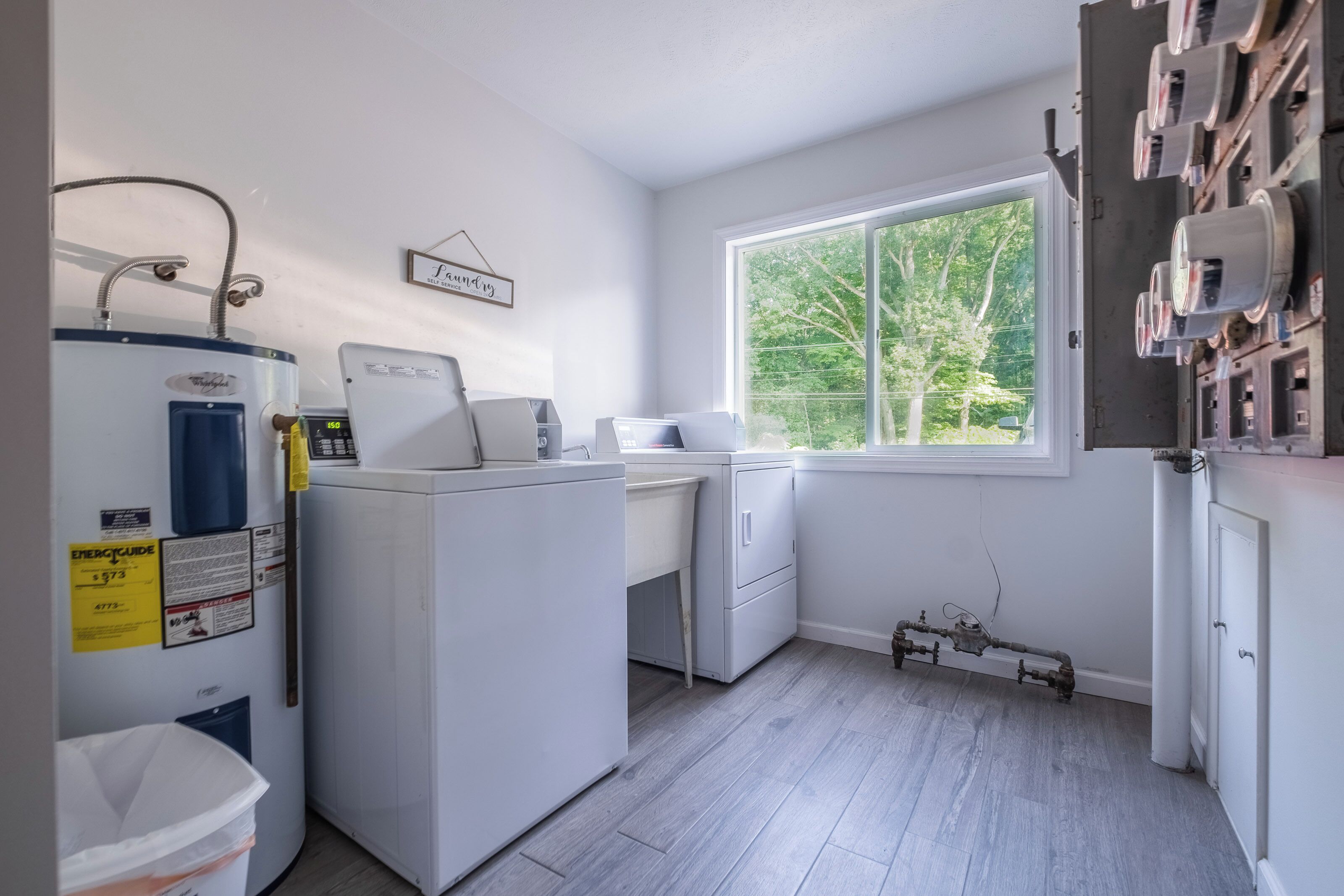 A laundry room with a washing machine, dryer, and a window with a view of trees.
