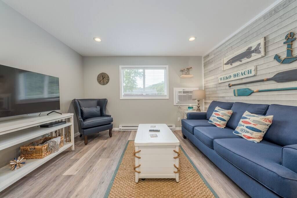A living room with a TV, a blue sofa, a white coffee table, and nautical decor.