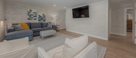 A modern living room with a grey sectional sofa, a white armchair, and a patterned rug.