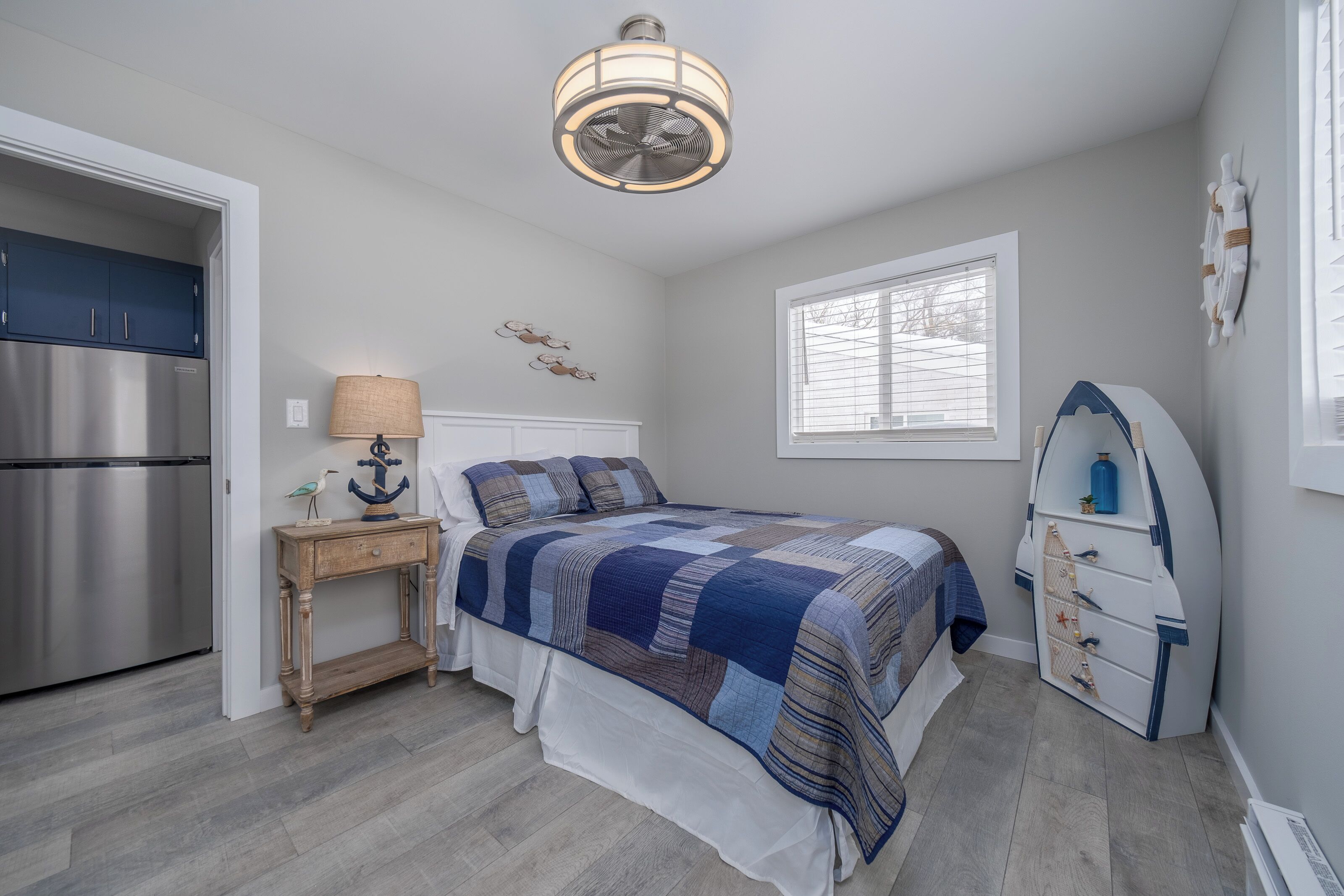 A bedroom with a bed, a nightstand, a lamp, a dresser, and a window.