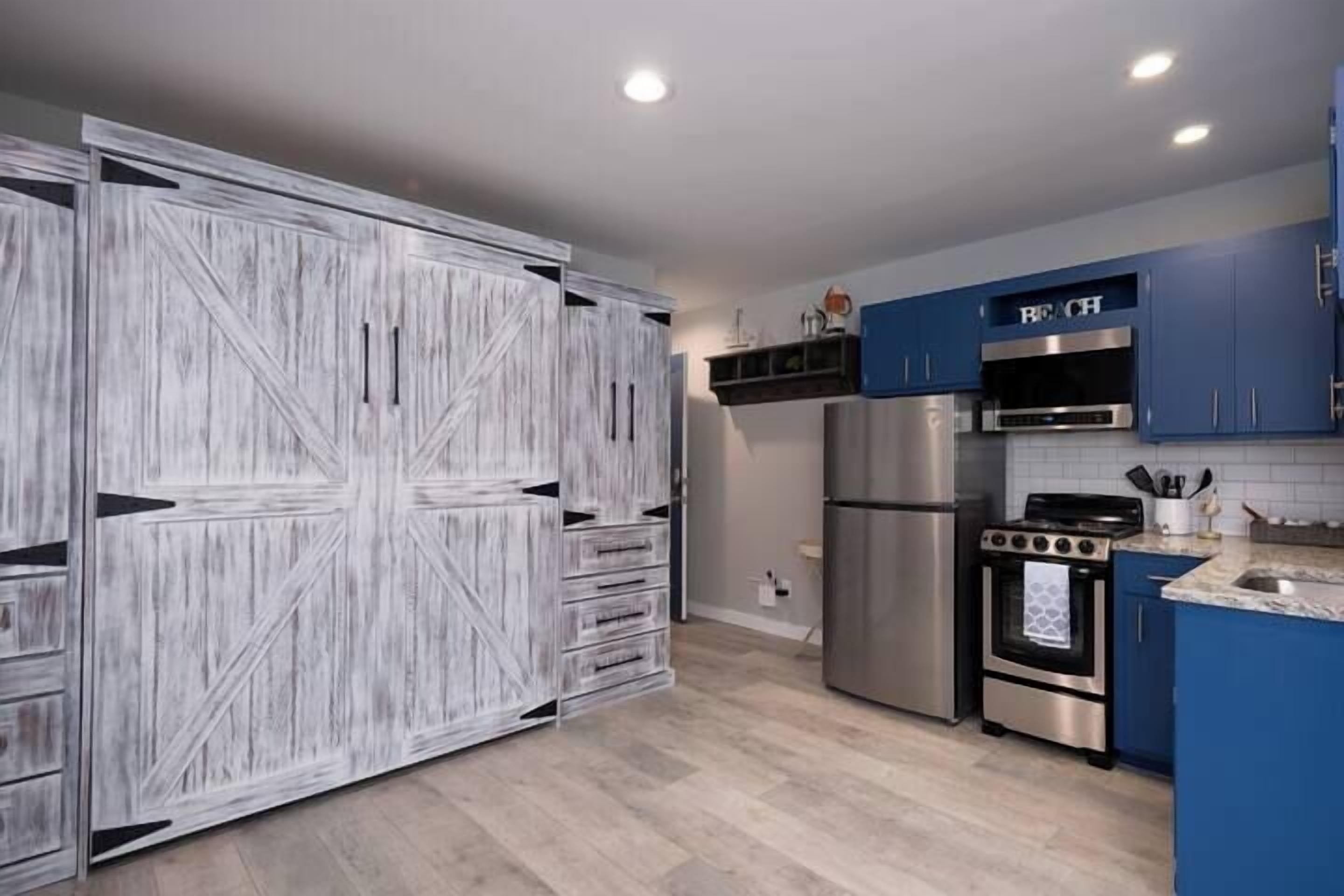 A modern kitchen with a large white wooden cabinet, stainless steel appliances, and blue cabinets.
