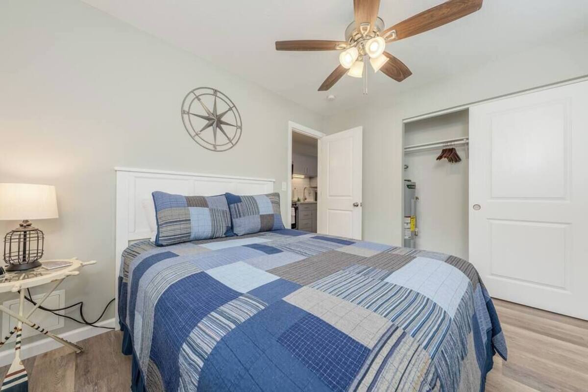 Une chambre à coucher avec un lit, un ventilateur de plafond, une horloge murale et un placard.