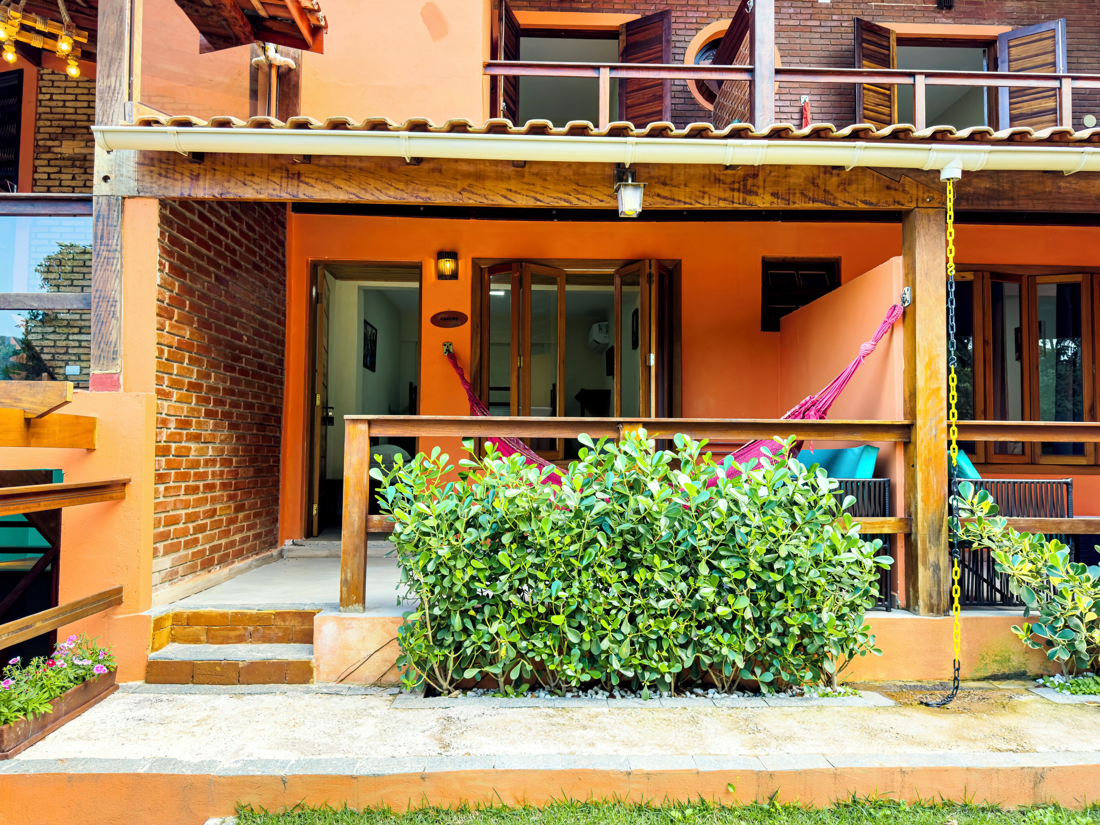 A building with a covered porch, a brick wall, and a staircase leading to an upper level.