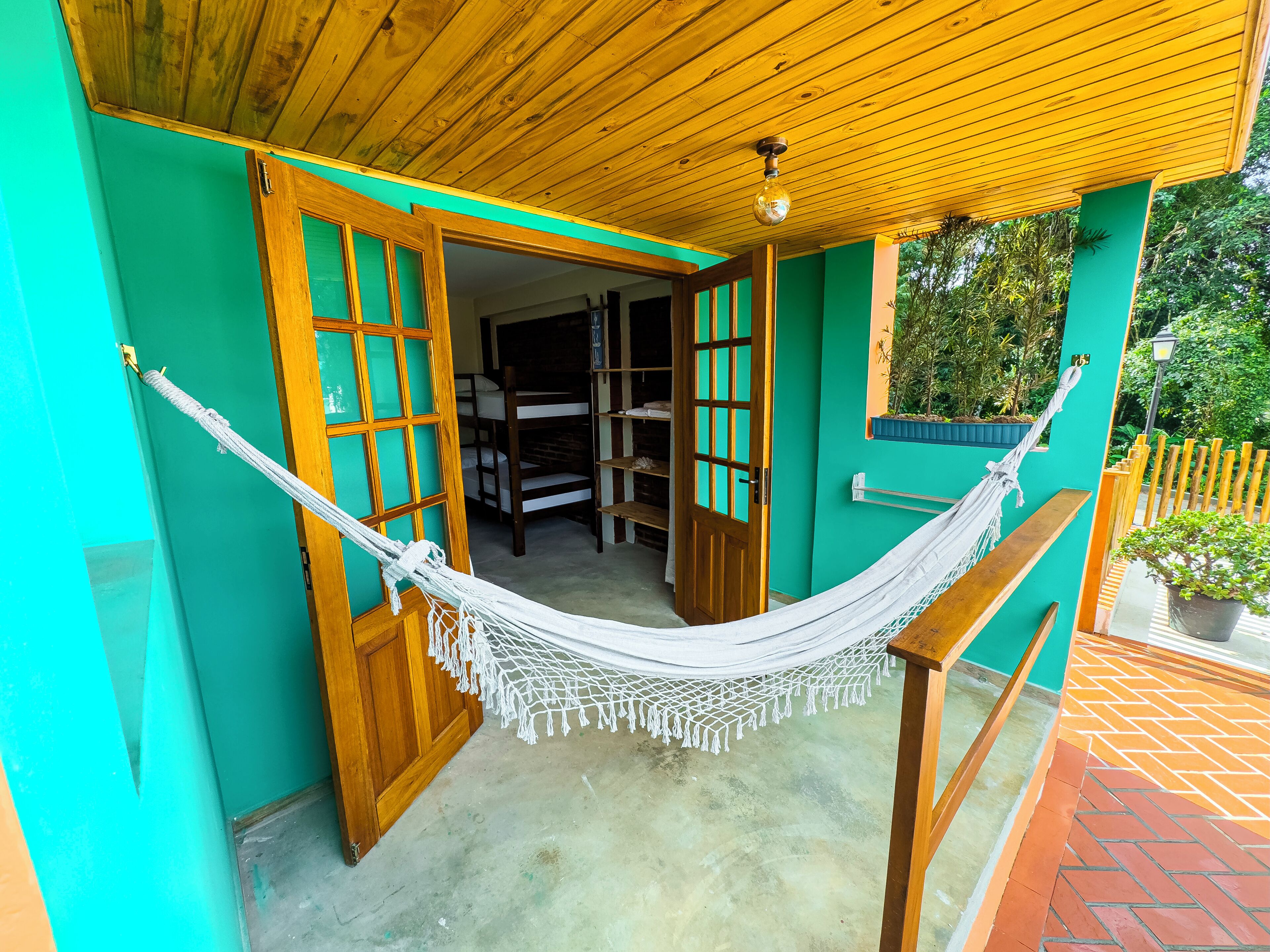 Una hamaca colgada entre dos puertas de madera, con vista a una habitación con literas.