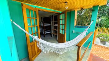 Una hamaca colgada entre dos puertas de madera, con vista a una habitación con literas.