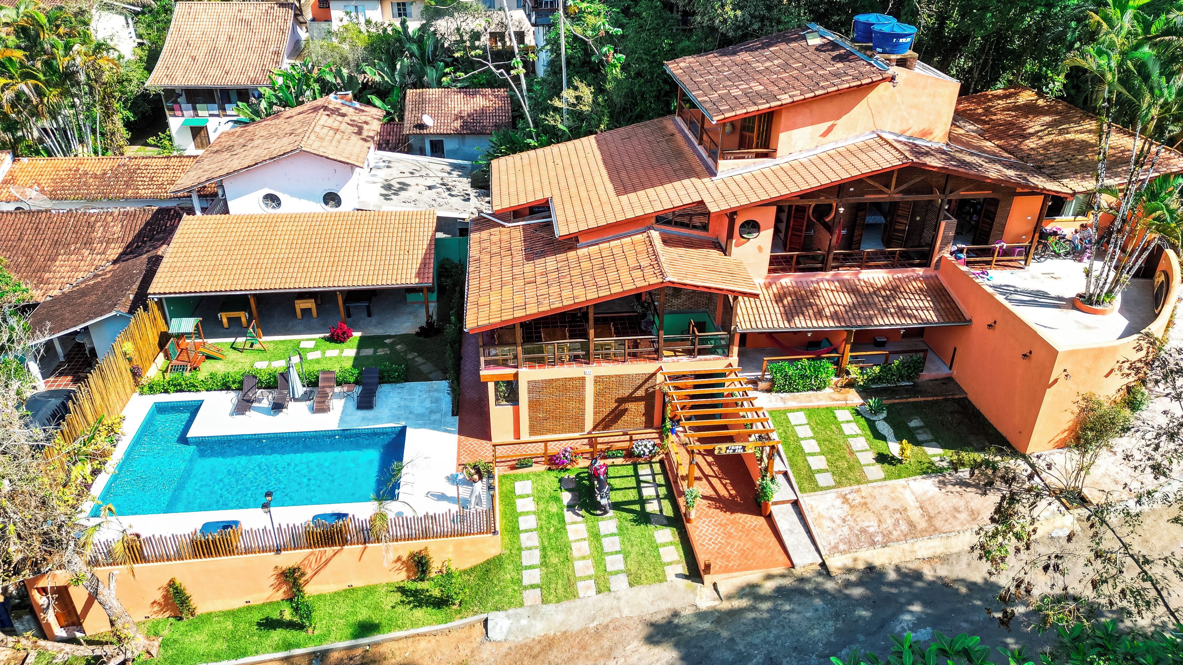 A large house with a swimming pool, multiple balconies, and a garden.