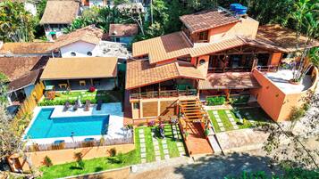 A large house with a swimming pool, multiple balconies, and a garden.