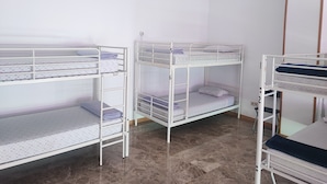 Een kamer met stapelbedden, een witte airconditioning en een betegelde vloer.