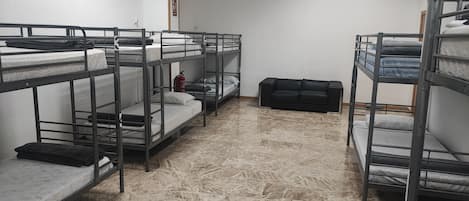 Un dormitorio con literas, un extintor y un sofá negro.