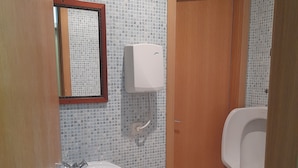 Een badkamer met betegelde wand, een wastafel, toilet en een houten deur.