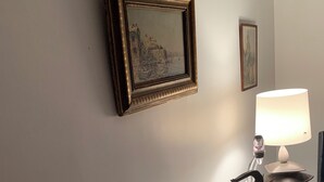 Una encimera blanca con una lámpara, un cuadro enmarco y un adorno decorativo.