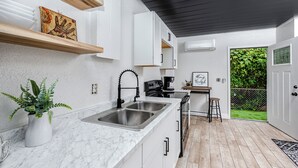 A modern kitchen with white cabinets, a marble countertop, and a coffee machine.