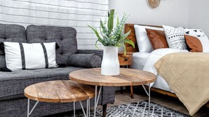 A modern living room with a grey sofa, a white vase with green plants, and a wooden coffee table.