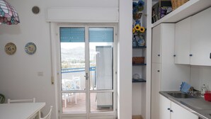 Een keuken met witte kasten, een RVS spoelbak en een eethoek met een witte tafel en stoelen.