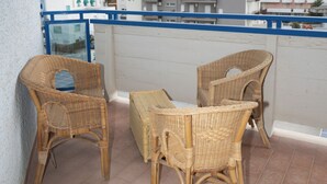 Een balkon met rieten meubilair en uitzicht op gebouwen.