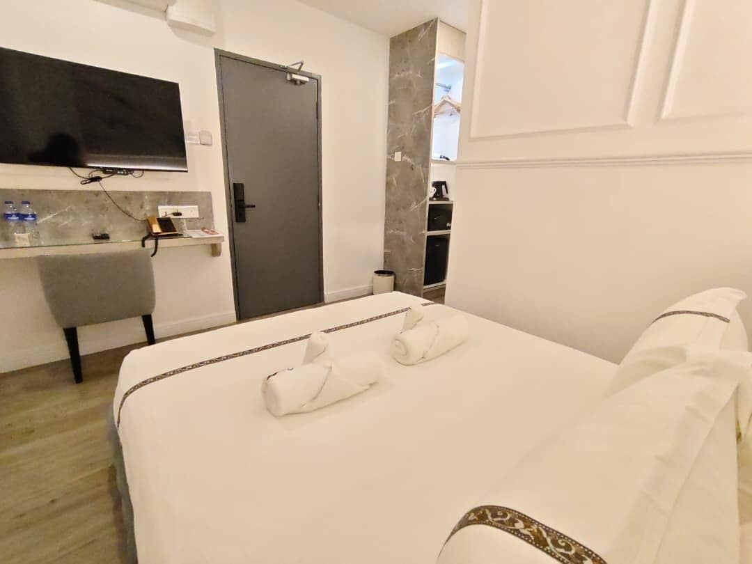 Una habitación de hotel con cama, escritorio, televisión y puerta.