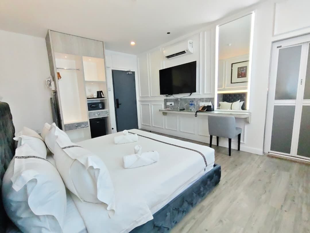 A hotel room with a bed, a desk, a television, and a sliding door.