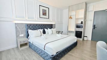 A modern bedroom with a large bed, bedside tables, a wardrobe, and a built-in desk.