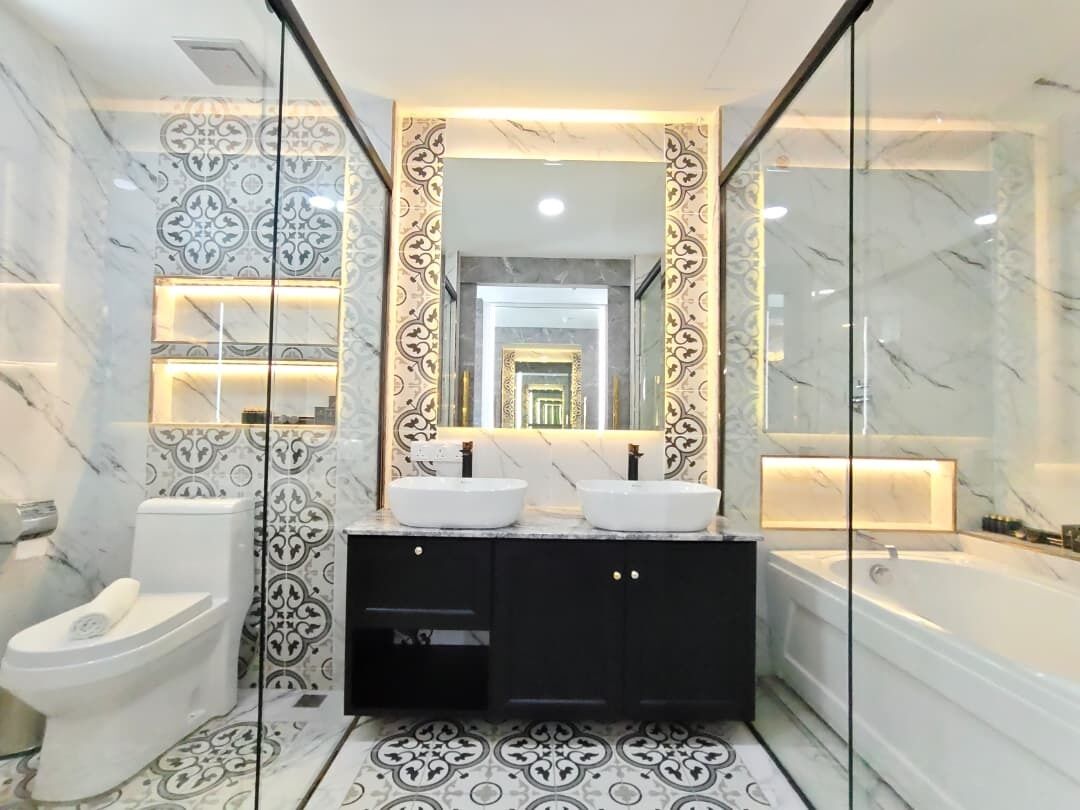 A modern bathroom with a double sink vanity, a toilet, and a bathtub.