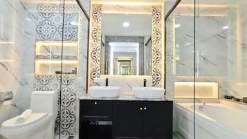 A modern bathroom with a double sink vanity, a toilet, and a bathtub.