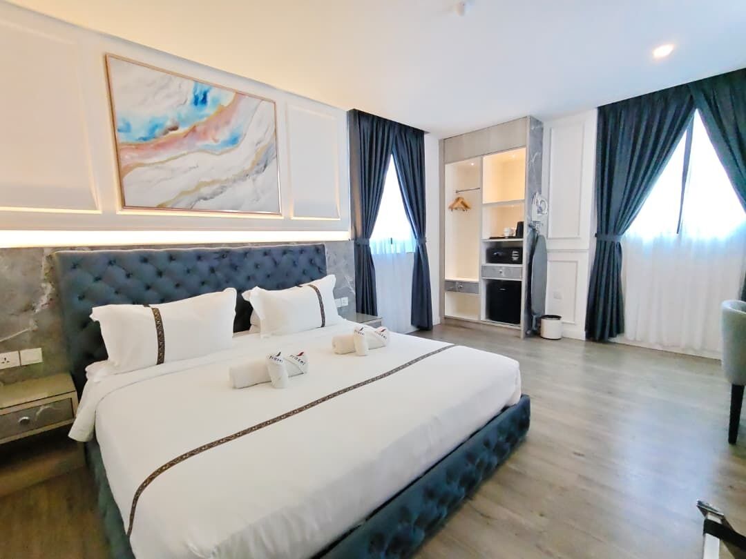 A hotel room with a large bed, a wardrobe, a desk, and a bathroom.