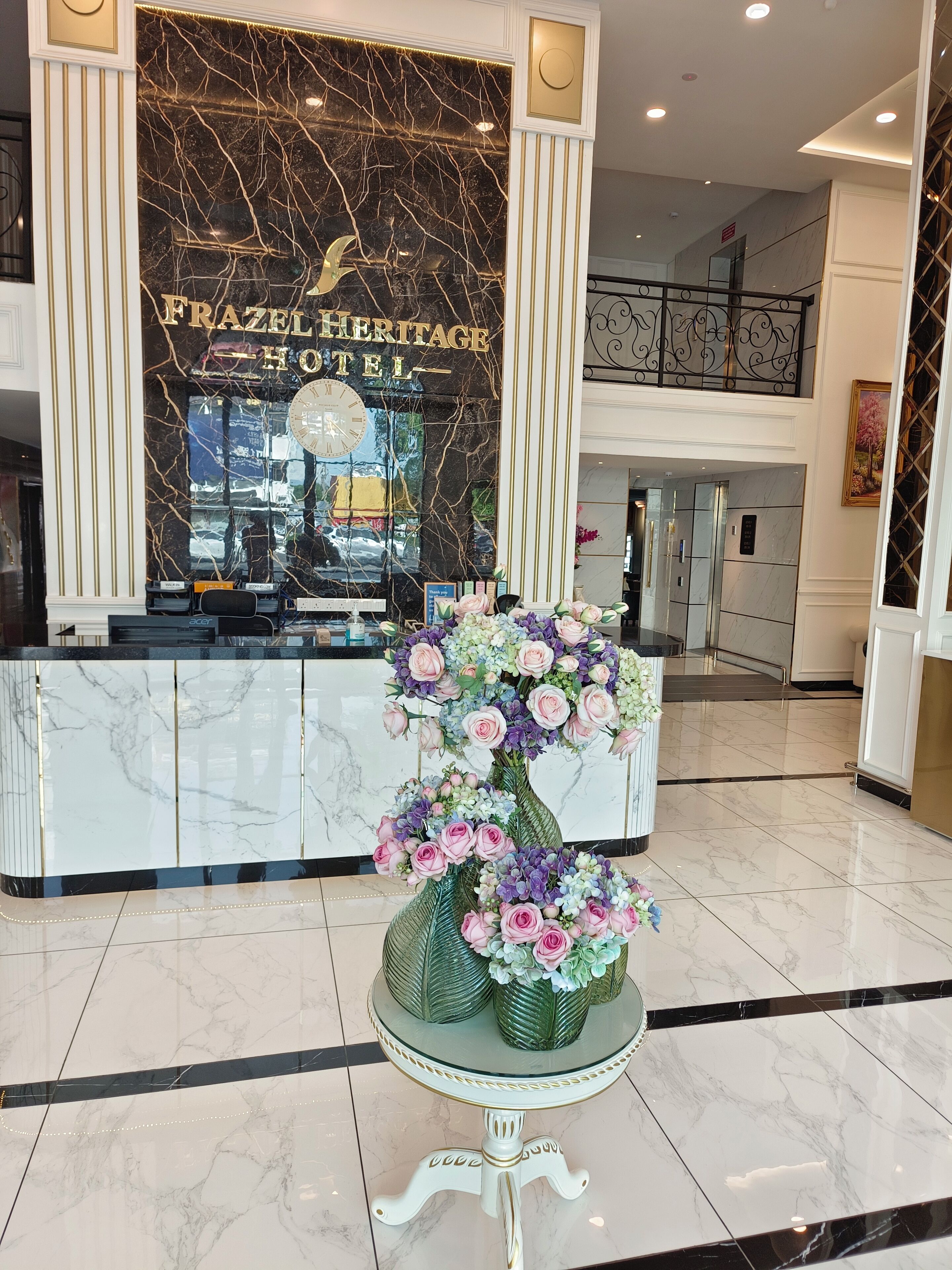 A reception area with a marble counter, a clock, and a floral arrangement.