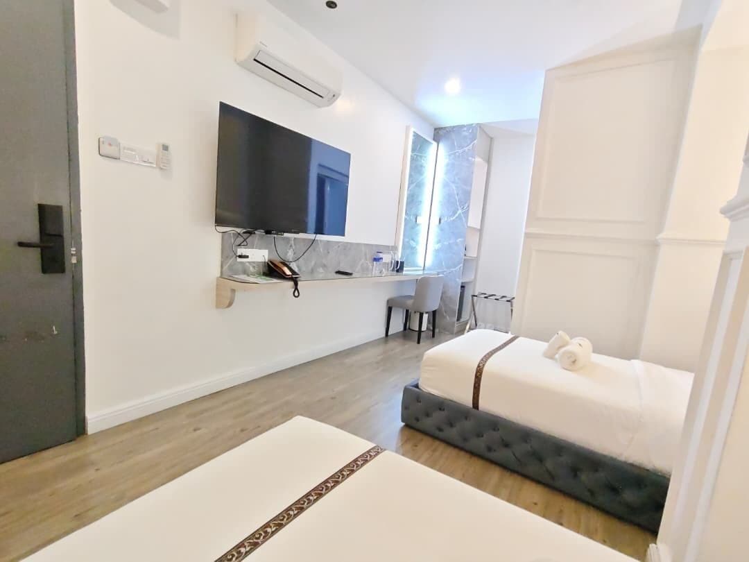 A modern hotel room with a bed, a TV, a desk, and a chair.
