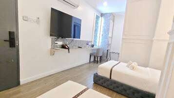 A modern hotel room with a bed, a TV, a desk, and a chair.