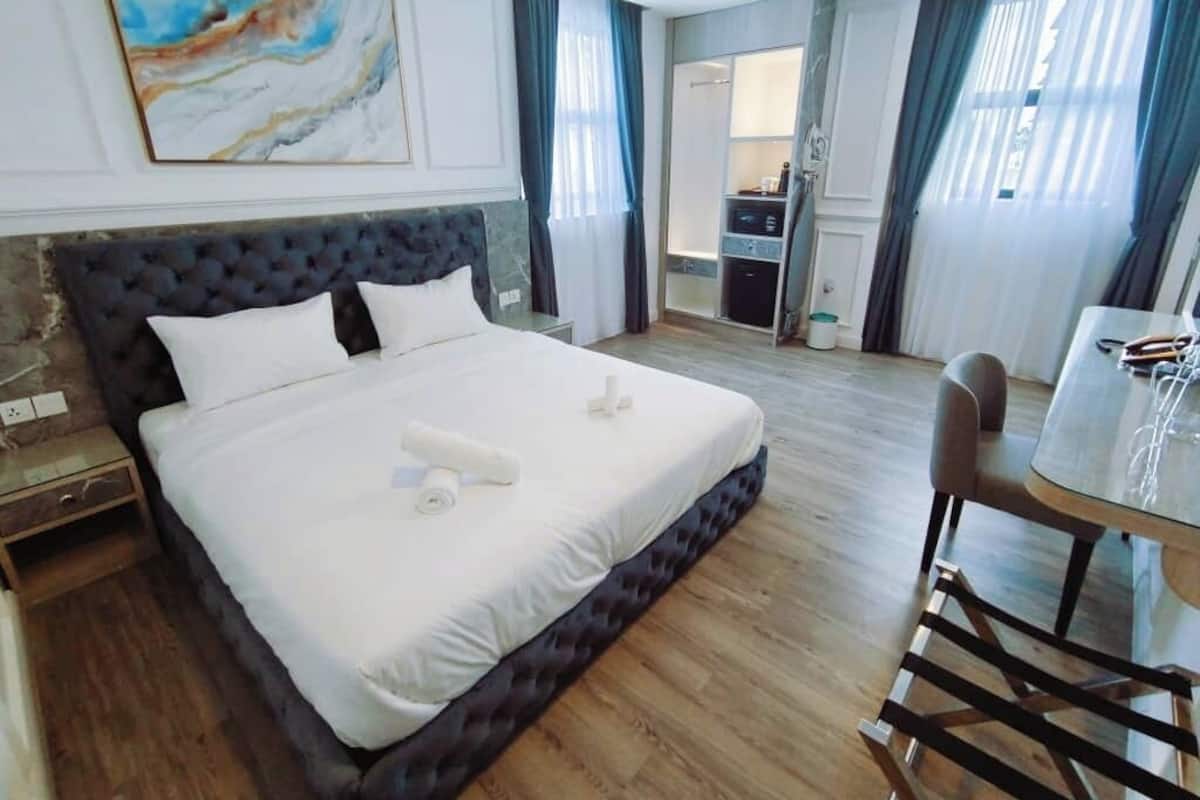 Hotellihuone, jossa on suuri sänky, yöpöytä, työpöytä ja tuoli.