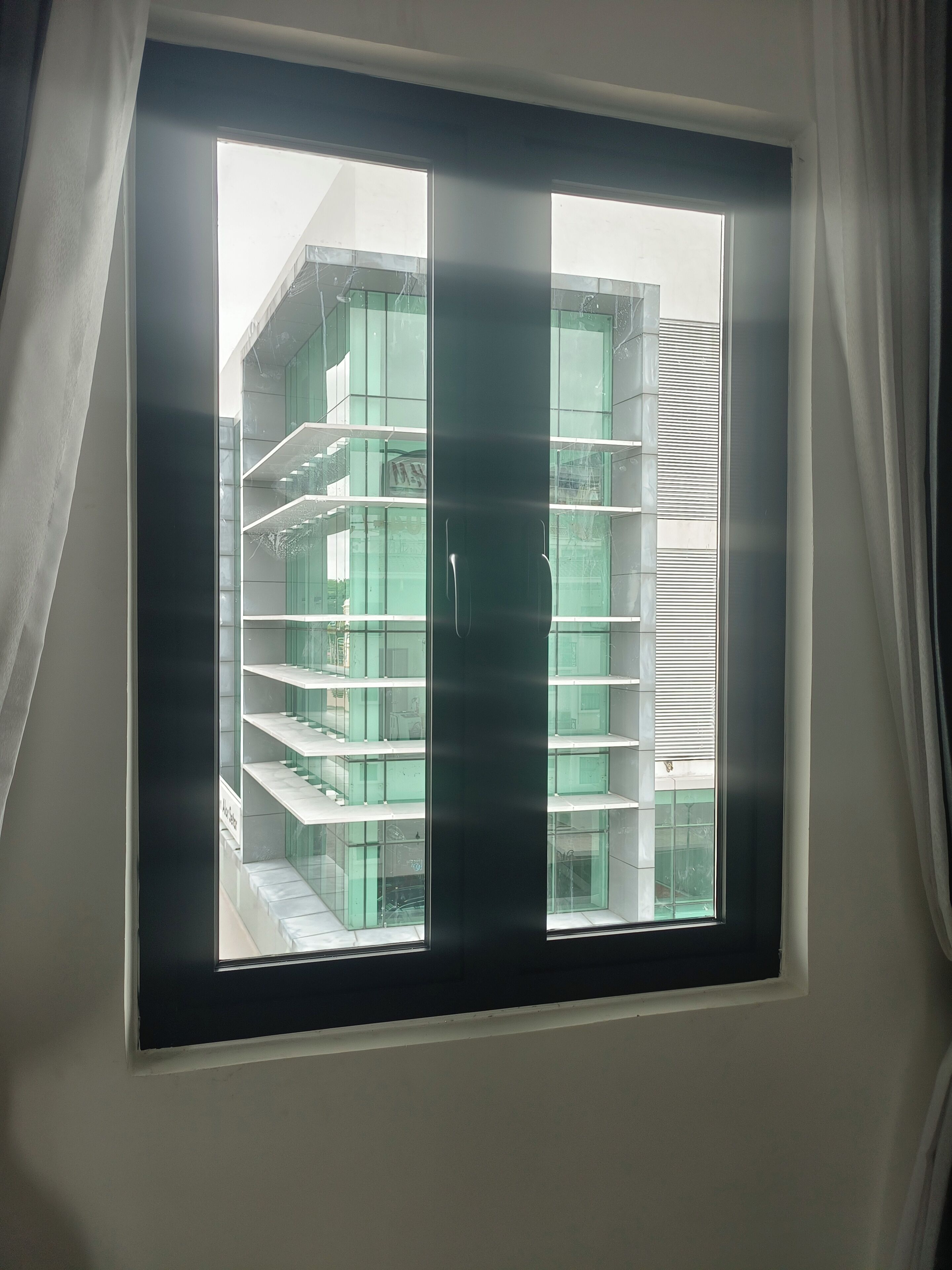 Una ventana con vista a un edificio de varios pisos y diseño moderno.