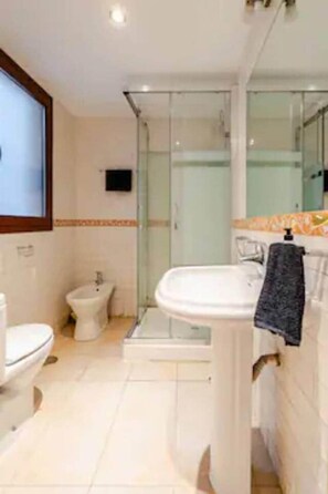 Un bany amb vàter, bidet i plat de dutxa amb envàs de vidre.