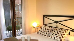 A hotel room with a bed, a bedside table with a lamp, a tray with cups and a flower, and a view of the outside balcony. - Acogedor, Luminoso y Céntrico 2a (Madrid)