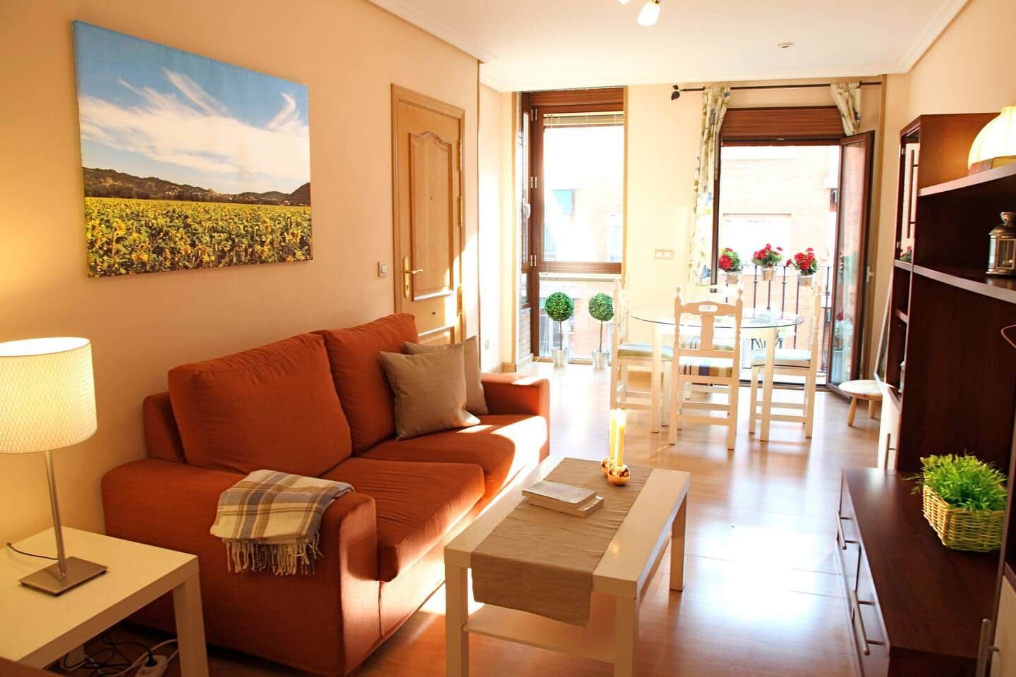 Una sala de estar con un sofá, una mesa de centro, una lámpara y un cuadro de un campo.