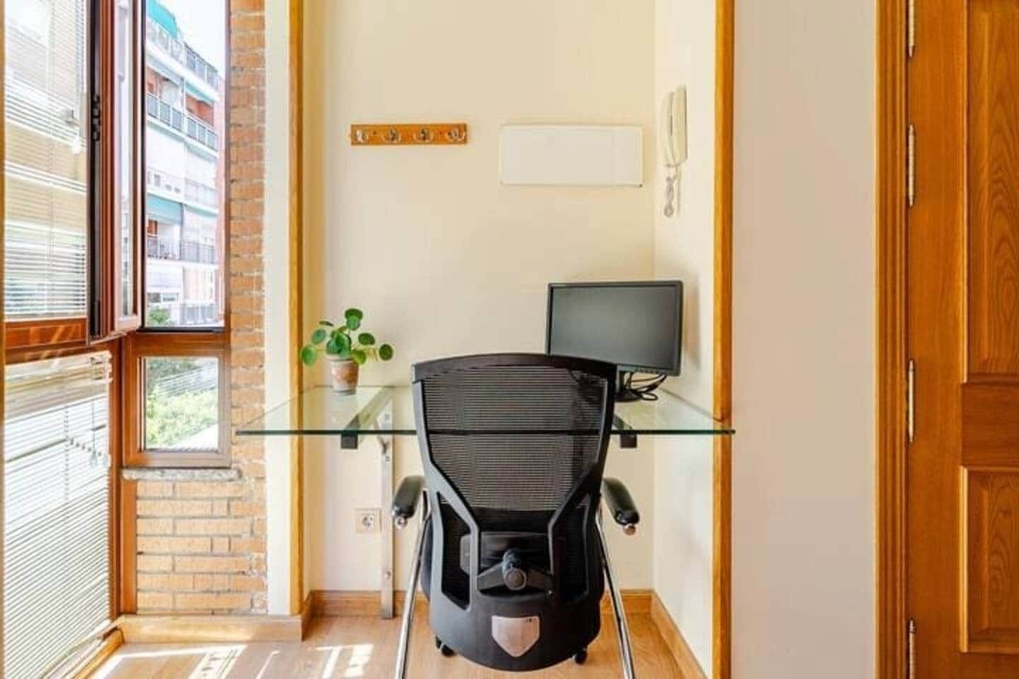 Un pequeño espacio de oficina con un escritorio, una silla, una computadora y una planta en maceta.