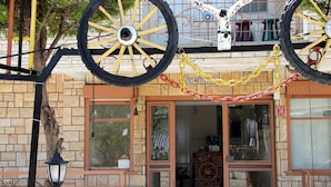 A hotel entrance with a large wooden door, a sign above the door, and a decorative wheel hanging above the entrance. - YAZICI (Edremit)