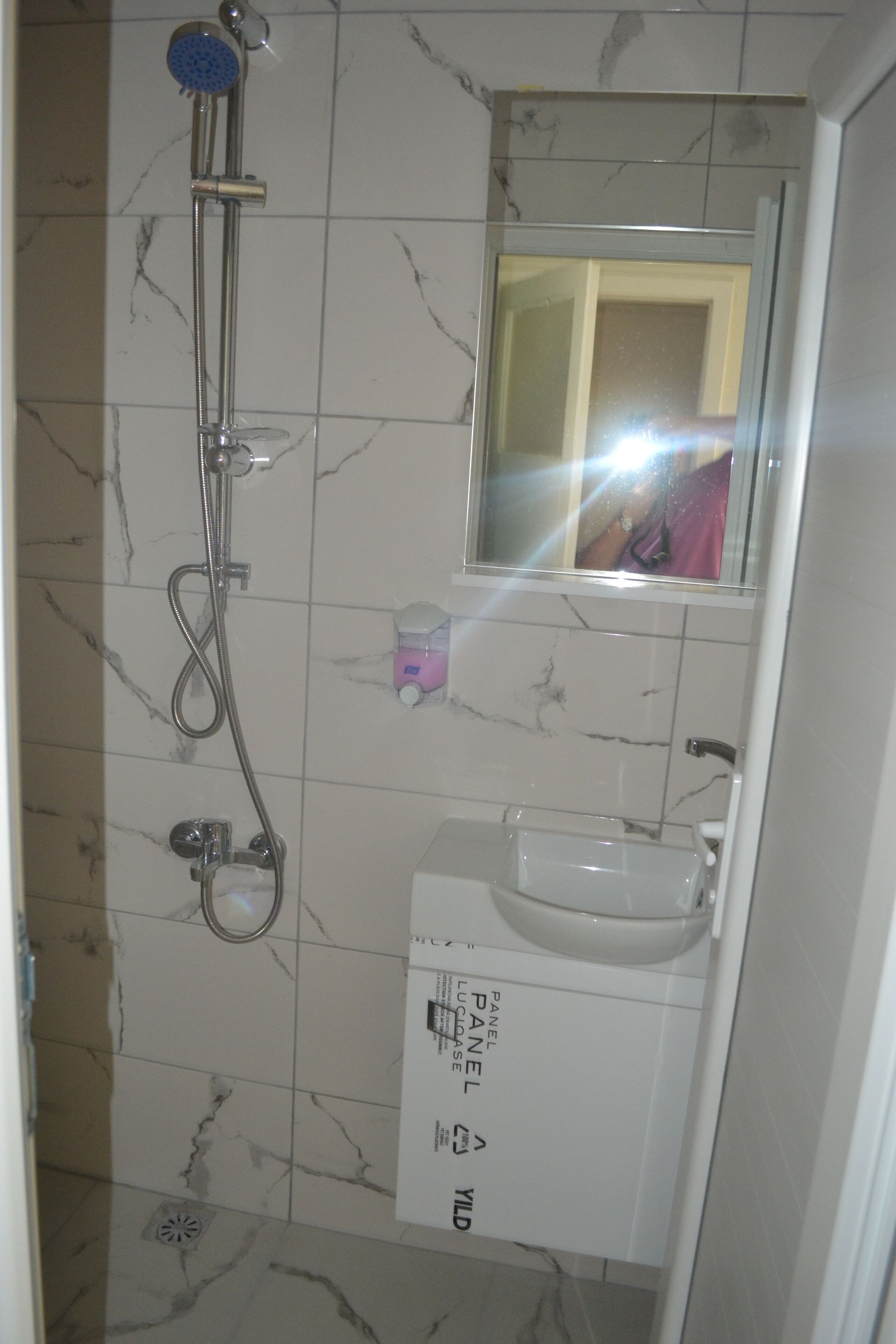 A bathroom with a shower, sink, and mirror.