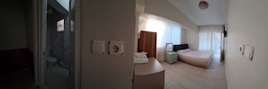 A hotel room with a bathroom, a bed, a bedside table, and a mirror.