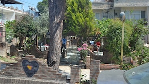 A courtyard with a heart-shaped mural, a tree, and a building with satellite dishes. - YAZICI (Edremit)