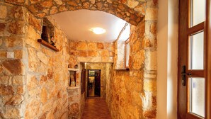 Un corridoio con pareti in pietra, una porta in legno e una finestra alla destra.