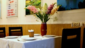 A dining table with a vase of flowers, a menu board, and a painting on the wall. - Hanoi Family Homestay (Hanoi)