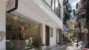 A narrow street with a coffee shop on the left, a motorcycle parked on the right, and buildings on both sides. - Hanoi Family Homestay (Hanoi)