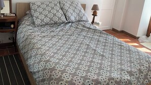 A bedroom with a bed, a nightstand, a lamp, and a framed picture on the wall.
