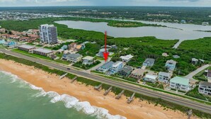Luftaufnahme einer Küstenregion mit Strand, einer Straße und Wohnhäusern.