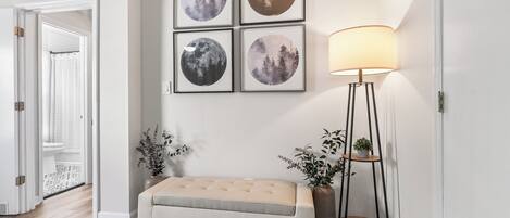 A hallway with a bench, a floor lamp, and framed moon pictures on the wall.