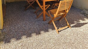 A wooden table with six chairs, a yellow drink, and a decorative wooden lattice overhead. - Lower villa F3 (Alata)