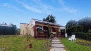 A house with a covered porch, a small garden, and a pathway leading to the entrance. - Le chalet du Lilas (Liessies)