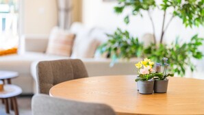 A round wooden table with potted plants and flowers in the foreground.