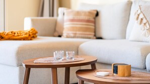 A cozy living room with a sofa, a small round table with glasses, and a decorative item on a side table.